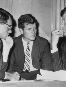 American politician brothers, US attorney-general Robert Kennedy (1925 - 1968), US senator Edward ‘Ted’ Kennedy, and US president John F. Kennedy (1917 - 1963) speak while seated behind a desk, circa 1962