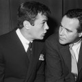 Tony Curtis and Jack Lemmon sit and talk at Milton Berle’s opening at the Cocoanut Grove, Hollywood, California on April 1, 1960
