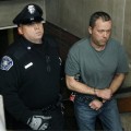Mark Kerrigan, the brother of figure skater Nancy Kerrigan, is led in handcuffs out of Woburn, Mass. District Court after his arraignment on January 25, 2010