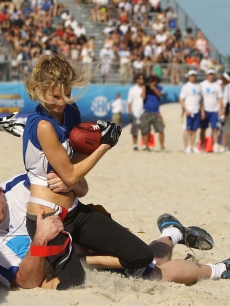 Tom Arnold tackles Marisa Miller during the DIRECTV Celebrity Beach Bowl on February 6, 2010 in Miami Beach, Florida