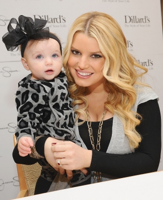 Jessica Simpson rocks her ruby engagement ring while holding a young fan at an in-store appearance at Dillard’s Oak Park in Overland Park, Kansas, on November 13, 2010  