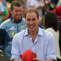 Prince William prepares to kick an AFL ball towards photographers while attending a community BBQ in Murrabit, Australia on March 21, 2011