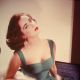 Elizabeth Taylor in a form-fitting green dress as she sits with her head tilted back exposing her neck, circa 1950s