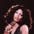 Donna Summer holding a microphone and looking upwards while singing, 1970s