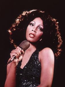 Donna Summer holding a microphone and looking upwards while singing, 1970s