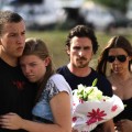 A couple embraces each other as Christian Bale holds flowers with his wife Sandra Blazic before placing them at the memorial in Aurora, Colorado July 24, 2012