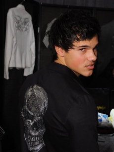 Taylor Lautner tries on a Glamour Campaign shirt at Access’ Stuff You Must lounge