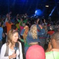 Maria Menounos films a segment while Bruce Springsteen performs in the background