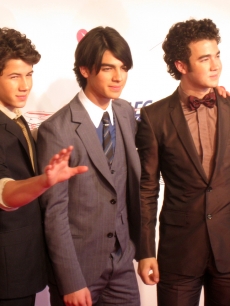 Nick waves as he poses with brothers Joe and Kevin Jonas at the MusiCares event, LA, Feb. 2009
