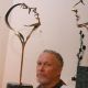 Patrick Farrow, brother of Mia, sitting with his bronze sculptures in May 2003