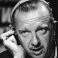 Closeup of Walter Cronkite speaking while listening to a headset circa 1968