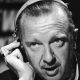 Closeup of Walter Cronkite speaking while listening to a headset circa 1968